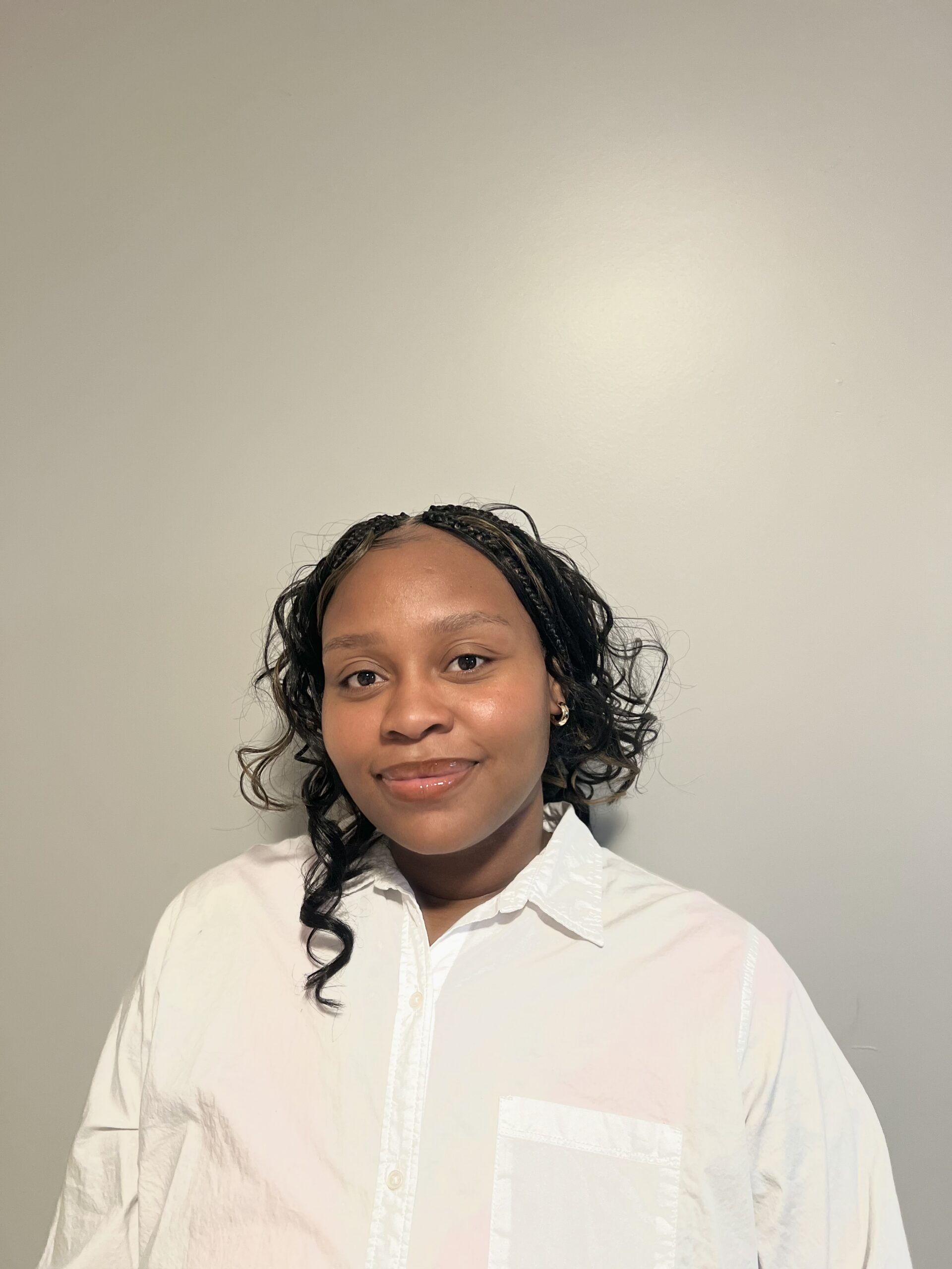 Kayon Morgan standing in front of a white wall and smiling at the camera