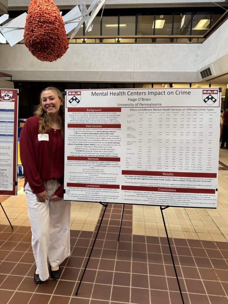 Paige O'Brien standing next to a poster display board with her research information on it