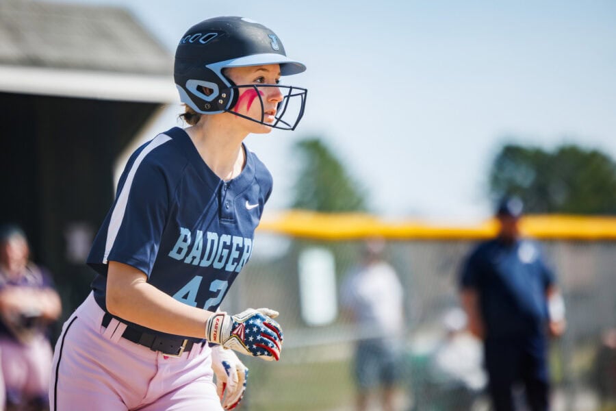 A young woman wearing a helmet running bases during a softball game
