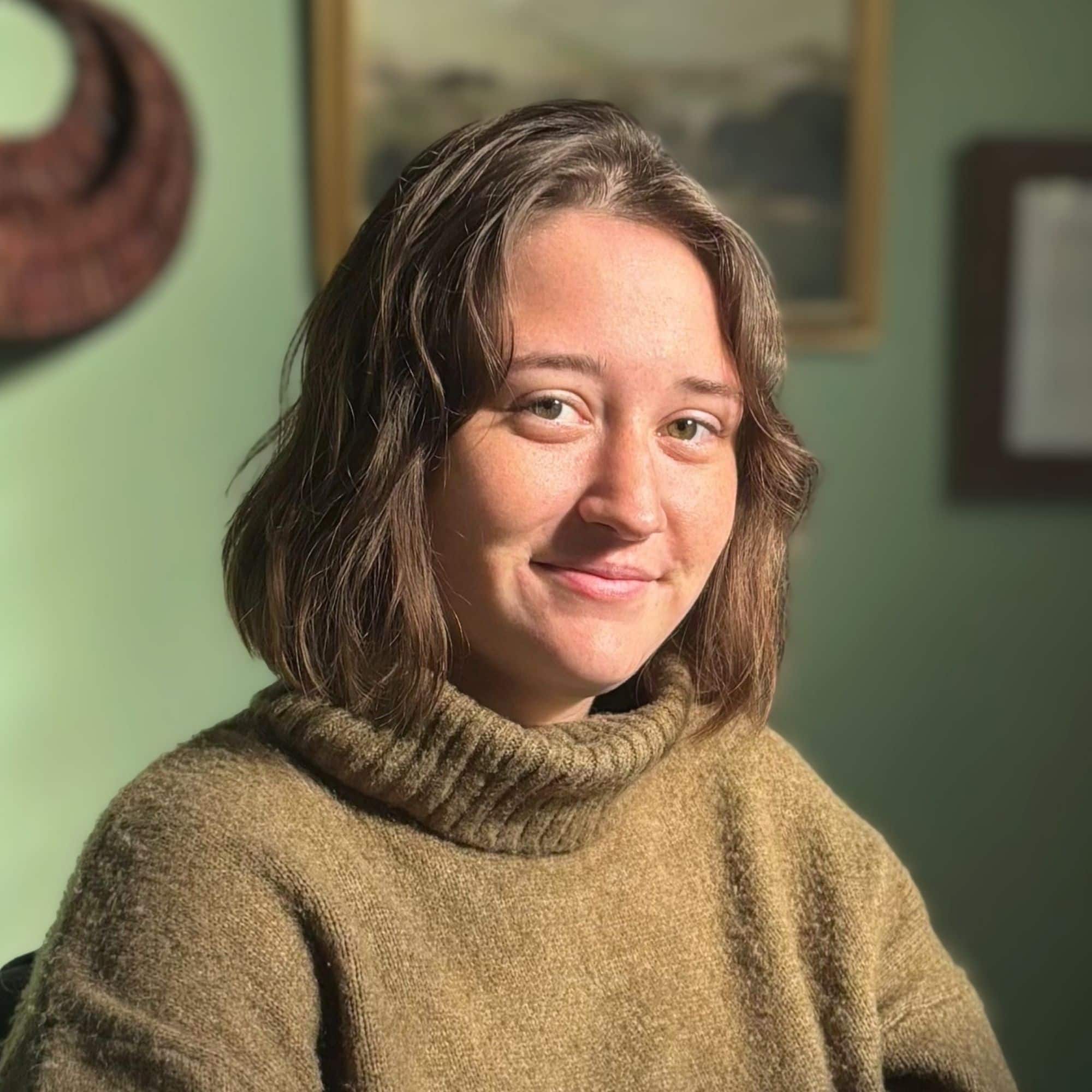 Molly Durling, a woman with shoulder-length wavy hair sitting in a green room and smiling at the camera