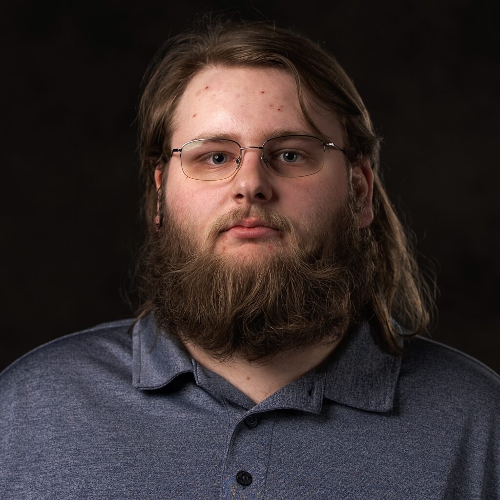 Robbie Oravsky standing in front of a dark backdrop and looking directly at the camera
