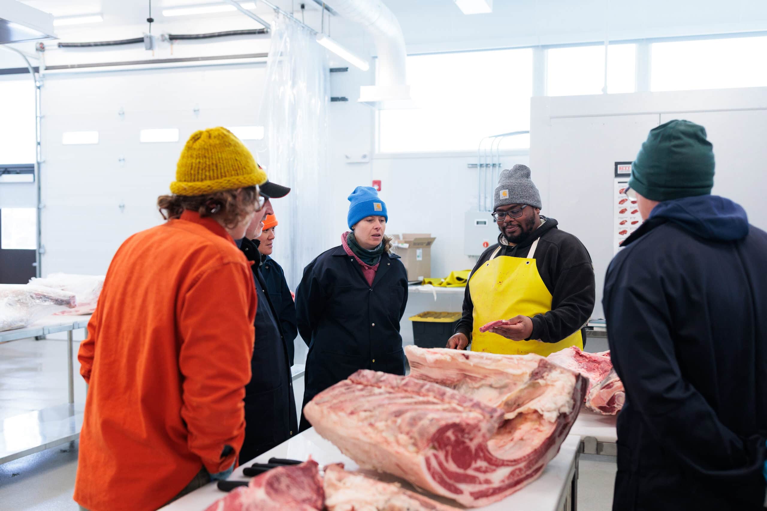 A group of people watching a butchery demonstration
