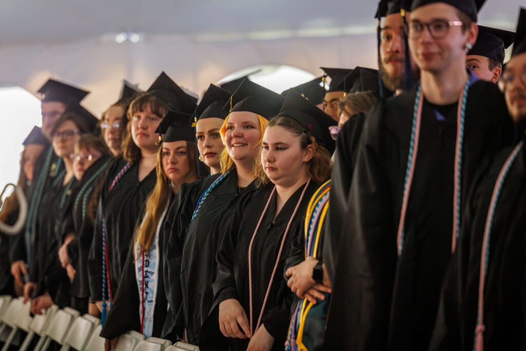 A group of graduates standing at their chairs