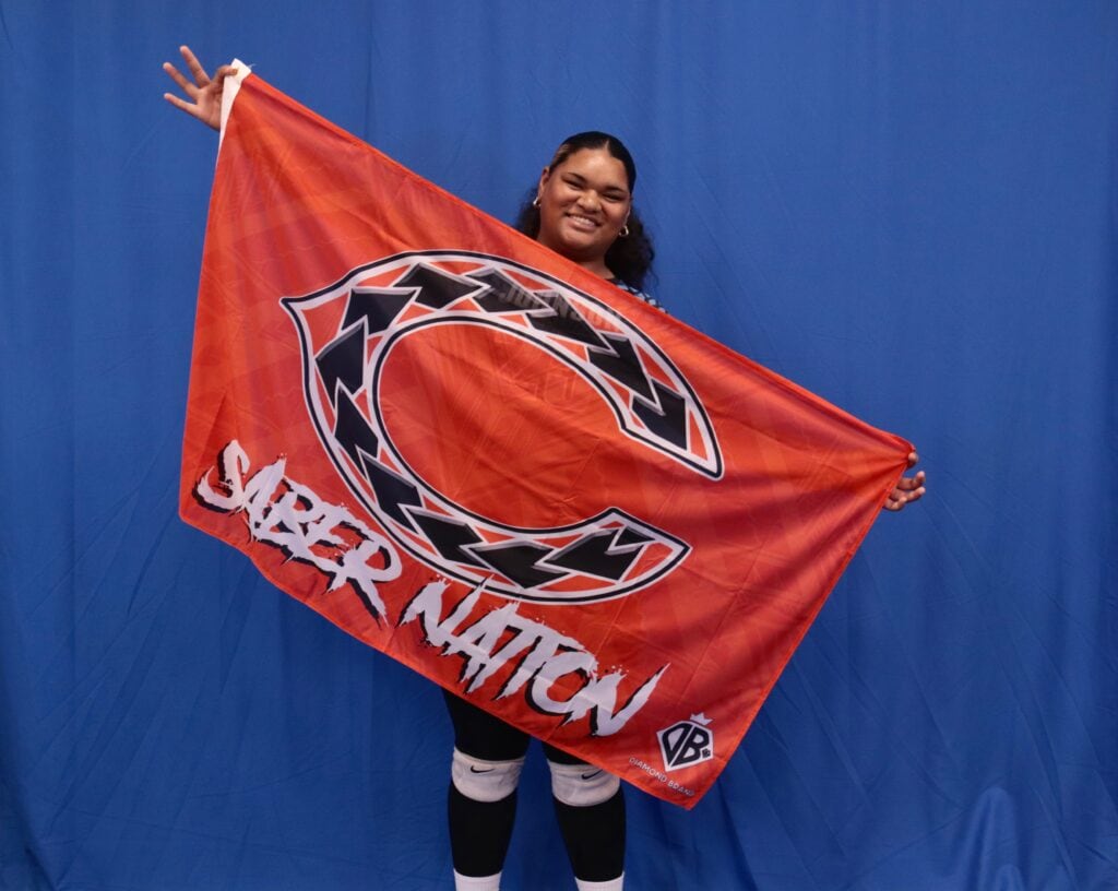 Sepphyre holding a large flag in outspread arms and smiling at the camera