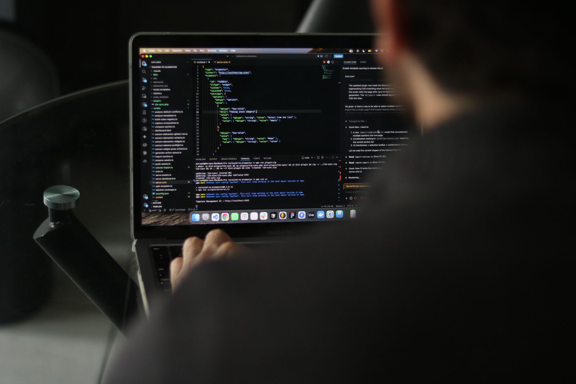 A man sitting at a laptop with his back to the camera, and a text editor on the screen