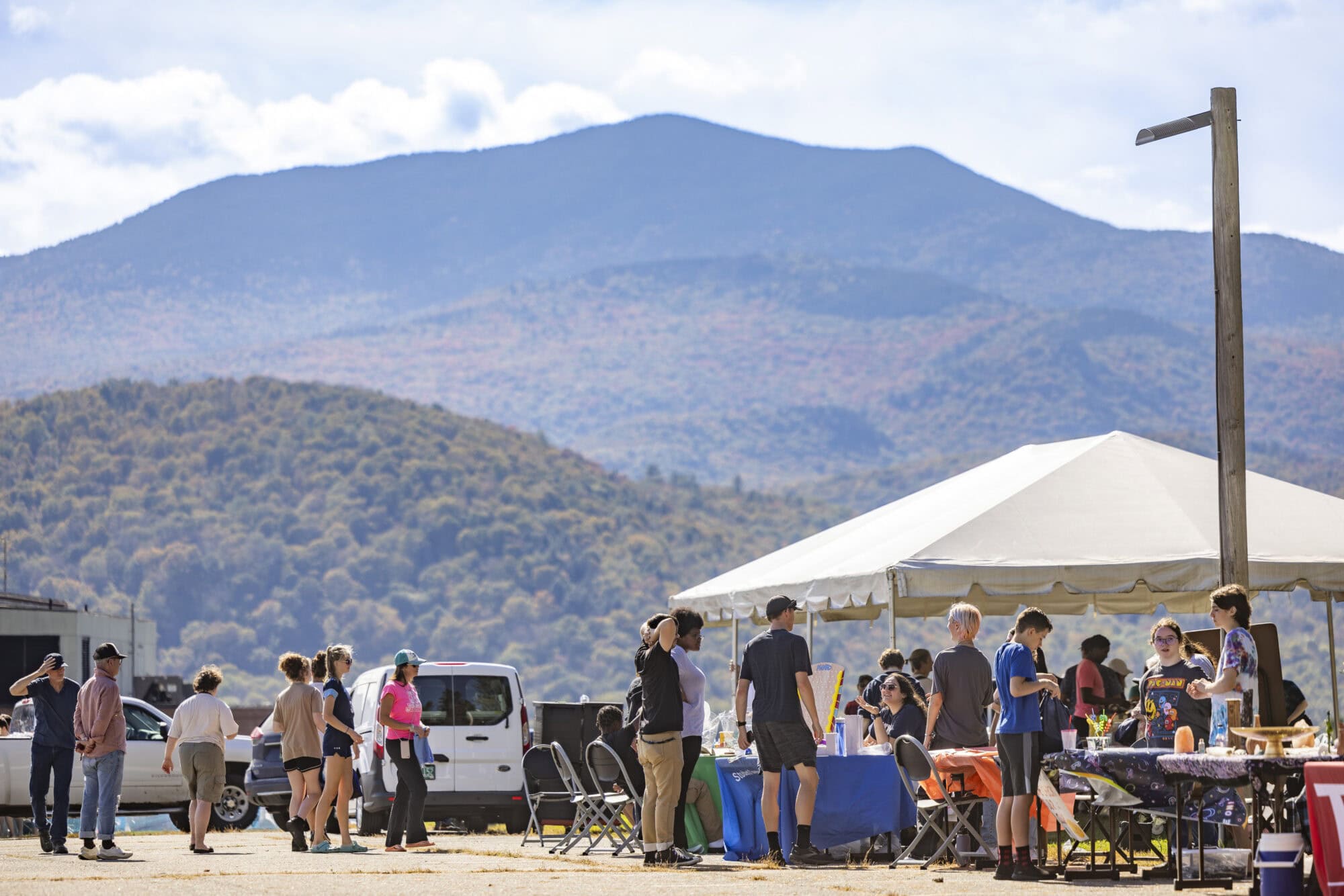 A group of people standing under pop-up tents at VTSU Johnson, with mountains in the background